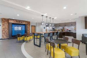 a dining room and kitchen with yellow chairs and tables at Best Western Plus Denton Inn & Suites in Denton