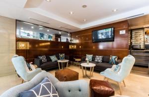 a waiting room with couches and a flat screen tv at Leonardo Hotel Barcelona Gran Via in Barcelona