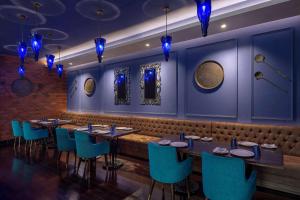 a dining room with tables and blue chairs at Radisson Blu Kaushambi Delhi NCR in Ghaziabad