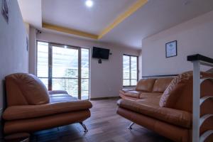 sala de estar con 2 sofás de cuero y TV de pantalla plana en Hotel Boutique Mardeka en Orizaba