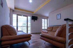 a living room with two leather couches and a flat screen tv at Hotel Boutique Mardeka in Orizaba