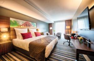 Una habitación de hotel con una cama grande y un escritorio. en Leonardo Royal Hotel Ulm, en Ulm