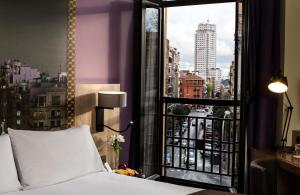 a bedroom with a bed and a window with a city view at Leonardo Hotel Madrid City Center in Madrid