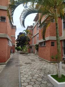 a courtyard with a palm tree next to a building at Apartamento Paraíso das Dunas em Cabo Frio in Cabo Frio