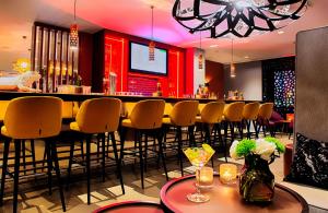 a bar in a restaurant with yellow bar stools at NYX Hotel Mannheim by Leonardo Hotels in Mannheim
