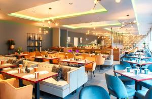 a restaurant with tables and chairs and a bar at NYX Hotel Mannheim by Leonardo Hotels in Mannheim