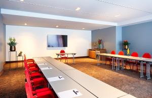 une salle de conférence avec des tables et des chaises rouges dans l'établissement NYX Hotel Mannheim by Leonardo Hotels, à Mannheim