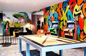マンハイムにあるNYX Hotel Mannheim by Leonardo Hotelsの卓球台と壁画のある部屋
