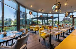 un restaurante con mesas, sillas y ventanas grandes en Leonardo Hotel Verona en Verona