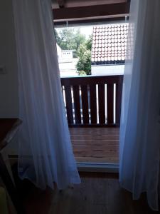 a window with a white curtain next to a balcony at Lamm - Wohnung 1 in Spiegelberg