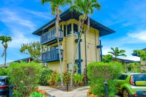 a yellow house with blue balconies and palm trees at View House Tower! in Princeville