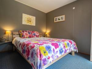 a bedroom with a bed with a colorful bedspread at Witte Bungalow in Uden