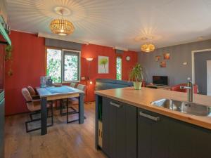 Witte Bungalow في أودن: مطبخ بجدران حمراء وطاولة مع حوض