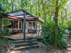 a small cottage with a deck in the woods at Berghuisje in Uden