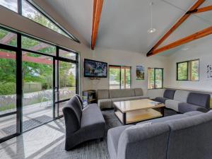 un soggiorno con divani, tavolo e finestre di Wanaka Top 10 Holiday Park a Wanaka