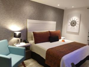 Habitación de hotel con cama y silla en Real Inn Celaya, en Celaya