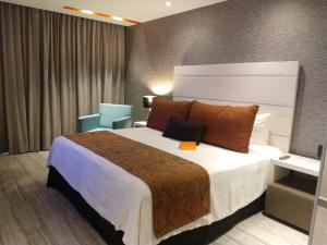 una habitación de hotel con una cama grande y una silla en Real Inn Celaya, en Celaya
