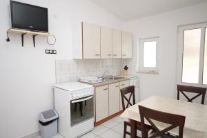 a kitchen with white cabinets and a table and a tv at Apartments by the sea Metajna, Pag - 6336 in Metajna