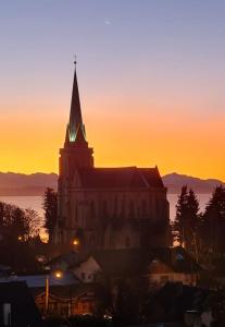 a church with a clock tower at sunset at Suite Vintage Bariloche in San Carlos de Bariloche