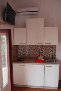 una cocina con armarios blancos y fregadero en Apartments and rooms with parking space Icici, Opatija - 7881, en Ičići