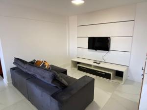 sala de estar con sofá y TV de pantalla plana en Apartamento com piscina Condomínio Balneário Camboriú, en Balneário Camboriú