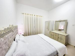 a white bedroom with a bed and a mirror at Cheap Holiday Home in Ajman 