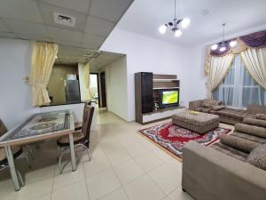 sala de estar con sofá, mesa y TV en Cheap Holiday Home, en Ajman