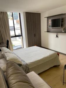 ein Hotelzimmer mit 2 Betten und einem Sofa in der Unterkunft Apartaestudio Galerias LOFT 2051 in Bogotá