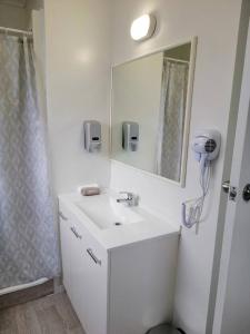 a white bathroom with a sink and a mirror at Stanley Apartments in Hamilton