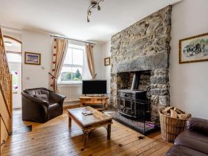 a living room with a stone fireplace and a tv at Glan Nug in Pentrefoelas