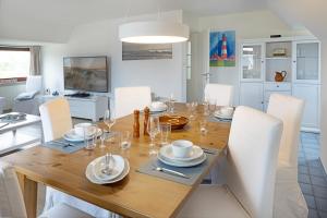 a dining room with a wooden table and white chairs at Captains Home in List