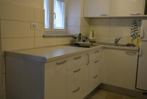 een keuken met witte kasten, een wastafel en een raam bij Apartments by the sea Cres - 15171 in Cres