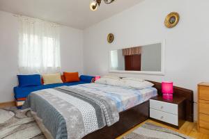 een slaapkamer met een blauw bed en een spiegel bij Apartments by the sea Pisak, Omis - 15177 in Mimice