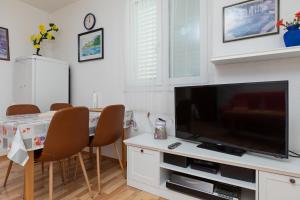 uma sala de estar com uma mesa e uma grande televisão em Apartment Pisak 15177b em Mimice