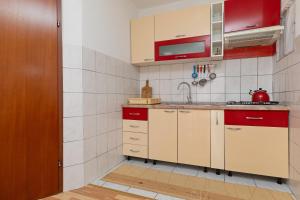 uma cozinha com armários vermelhos e brancos e um lavatório em Apartment Pisak 15177b em Mimice