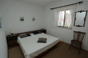 a bedroom with a bed and a chair and a window at Apartments with parking space Splitska, Brac - 15197 in Splitska