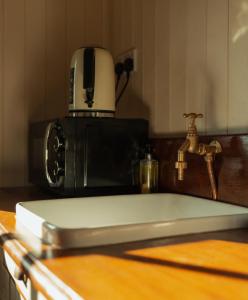 a kitchen counter with a sink and a toaster at Glamping in Wiltshire in our luxury Shepherds Hut in Chippenham