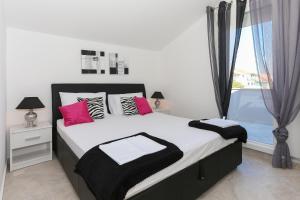 1 dormitorio con 1 cama con almohadas rosas y negras en Apartments by the sea Tribunj, Vodice - 15233, en Tribunj