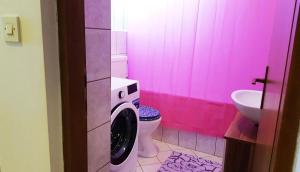 een roze badkamer met een wasmachine en een toilet bij Apartments with a parking space Senj - 15236 in Senj