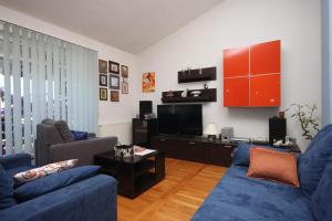 salon z niebieską kanapą i telewizorem w obiekcie Apartments with a parking space Makarska - 9696 w Makarskiej