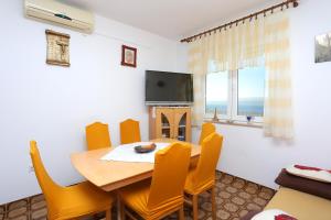 ein Esszimmer mit einem Tisch, Stühlen und einem TV in der Unterkunft Apartments with a swimming pool Mali Rat (Omis) - 9698 in Dugi Rat