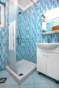 a blue tiled bathroom with a shower and a sink at Apartment Stara Novalja 9368b in Novalja