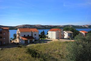 a row of houses on a hill next to the water at Apartment Stara Novalja 9368b in Novalja