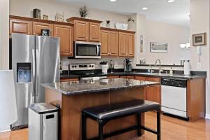 a kitchen with wooden cabinets and a stainless steel refrigerator at Comfortable Townhouse - Short Stroll to Notre Dame in South Bend