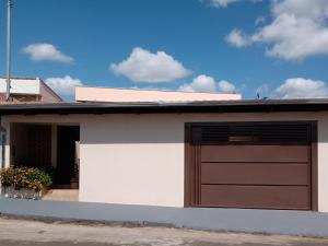 une porte de garage sur une maison blanche et brune dans l'établissement Piscina Aquecida, Ar condicionado Casa Inteira,Caminhos da Canastra, à São João Batista do Glória