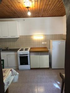 La cuisine est équipée d'une cuisinière blanche et d'un réfrigérateur. dans l'établissement Apartments by the sea Susak, Losinj - 14713, à Susak