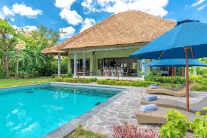 a villa with a swimming pool with two chairs and an umbrella at The North Cape Beach Villas in Umeanyar