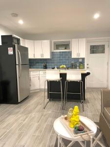 a kitchen with a refrigerator and a table in it at Modern apartment with parking & quick ride to Manhattan in Cedar Manor