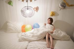 a young girl laying on a bed under a blanket at Transit House 5S Terminal in Chatan