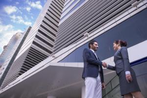 a man and woman shaking hands in front of a building at Nassima Tower Hotel Apartments in Dubai
